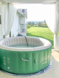 an inflatable swimming pool on the back porch of a house with curtains over it