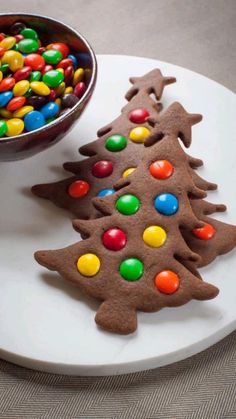 two decorated cookies sitting on top of a plate next to a bowl filled with candy