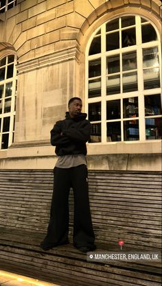 a man standing in front of a building with his arms crossed