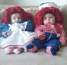 two baby dolls sitting next to each other on a couch