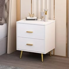 a white night stand with two gold handles on it next to a bed and nightstand