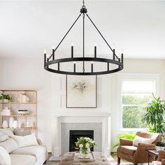 a living room filled with furniture and a fire place under a chandelier in front of a fireplace