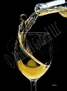 a wine glass filled with white wine being poured into it