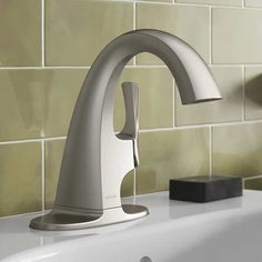 a faucet that is sitting on top of a sink in a room with tiled walls