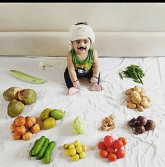 a baby sitting on the floor surrounded by fruits and vegetables