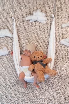 a baby laying in a hammock with a teddy bear