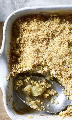 a casserole dish with a spoon in it and crumbs on the side