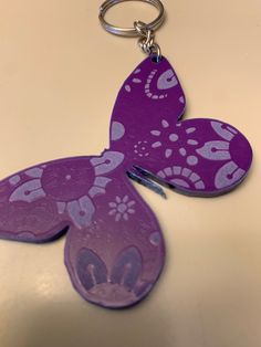 a purple butterfly shaped keychain sitting on top of a table