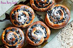 four cinnamon rolls on a plate with powdered sugar and chocolate toppings in the middle