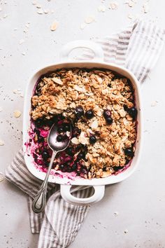 blueberry crisp with oats in a white dish on a gray and white towel