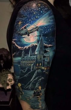 a woman's arm with a castle and plane on it, in the night