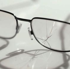 a pair of glasses sitting on top of a white table with the reflection of them in it