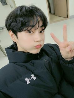 a young man making the peace sign with his hand while sitting in front of him