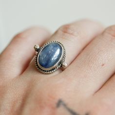 We are very excited about the look and feel of our new Deep Blue Kyanite Lasso Ring! This Boho Blue Kyanite Ring looks and feels great - you won't want to take it off! Perfectly balanced with a healthy sized 10X14mm Blue Kyanite stone, .925 Sterling silver accents and half-round shank - super comfortable and easy to wear. This ring's all sterling silver details are unique and truly set off the stone! You might want to make room on your hand -- you're going to want to wear this Blue Kyanite State Everyday Sapphire Ring Jewelry, Blue Untreated Oval Rings, Everyday Sapphire Ring, Spiritual Sapphire Oval Rings, Untreated Blue Sterling Silver Rings, Silversmith Rings, Lower Chakras, Kyanite Ring, Turquoise Gold Ring