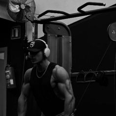 a man with headphones standing in front of a gym machine