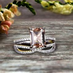 an engagement ring and wedding band set on a wooden table with flowers in the background