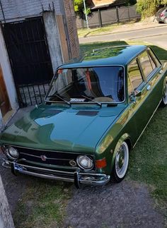 an old green station wagon parked in front of a building