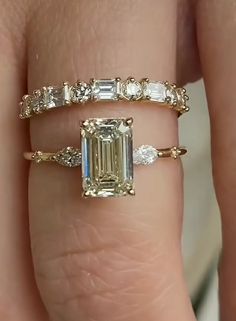 a woman's hand with two rings and an engagement ring on top of her finger