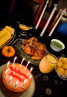 a birthday cake with candles on it sitting in front of other plates and bowls filled with food