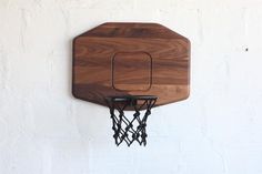 a basketball hoop mounted to the side of a white wall with a wooden backboard