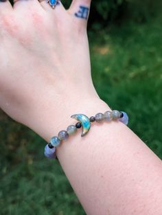 🌙This crystal bracelet is made from natural labradorite and iolite beads, separated by tiny silver sheen obsidian beads. In the center is a stunning labradorite moon with flash on both sides. 🌙This bracelet is made to comfortably fit up to a 7.75-inch wrist. Photo shows bracelet modeled on a 6.25 inch wrist. *Please note that all of our jewelry is handmade and may contain minor imperfections.  Other Information  ✨ Jewelry Care Instructions - Do not stretch the bracelet past the point of tensio Blue Labradorite Bracelets With Natural Stones, Adjustable Labradorite Gemstone Beads Bracelets, Labradorite Bracelets With Natural Stones For Healing, Adjustable Beaded Moonstone Bracelets With Natural Stones, Adjustable Labradorite Spiritual Crystal Bracelet, Blue Moonstone Bracelets For Healing, Blue Labradorite Bracelet As A Gift, Blue Moonstone Bracelet For Healing, Adjustable Labradorite Beaded Bracelets