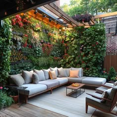 an outdoor living room with lots of plants on the wall and couches around it