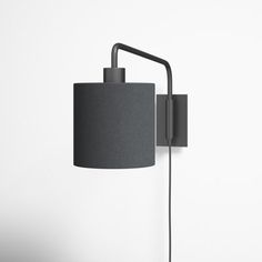 a black lamp on a white wall with a gray shade hanging from it's arm