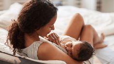 a woman laying on top of a bed holding a baby