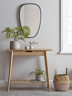 a wooden table topped with potted plants next to a mirror and wicker basket