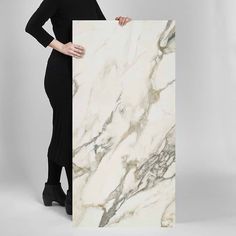 a woman holding up a large white marble board