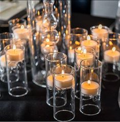 many candles are lit in clear glass vases