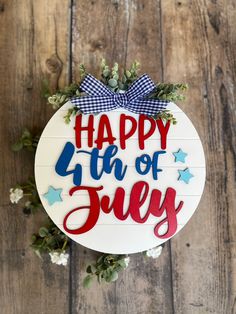 a sign that says happy 4th of july hanging on a wooden wall with flowers and greenery