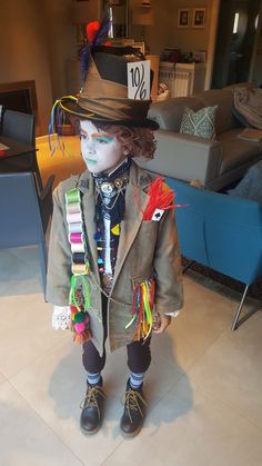 a doll dressed up as a boy in a suit and hat with feathers on his head