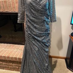 a silver dress is on display in front of a fire place and fireplace mantel