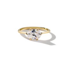 a yellow gold ring with an oval cut diamond on the center and two smaller round diamonds in the middle