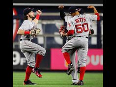 two baseball players in grey and red uniforms are on the field with their hands up