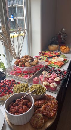 an assortment of desserts and pastries on a table in front of a window