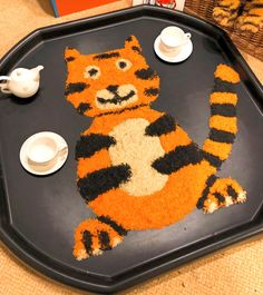 a tray that has a tiger rug on it with tea cups and saucers next to it