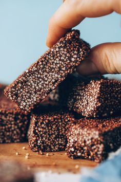 a hand is picking up some brownies from a pile