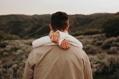 a man with his back to the camera, wearing a tan jacket and white shirt