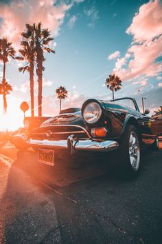 a classic car parked in front of palm trees