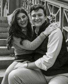 a man and woman sitting on the steps smiling at the camera with their arms around each other