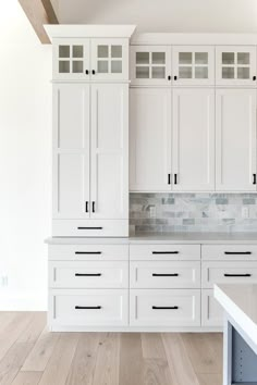 an empty kitchen with white cabinets and marble counter tops in the middle of the room