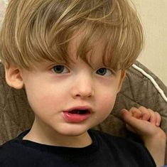 a little boy sitting in a chair looking at the camera