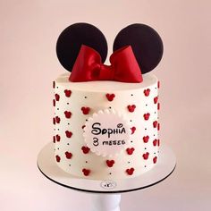 a white cake decorated with red and black minnie mouse ears