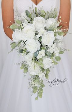 a bridal holding a bouquet of white flowers and greenery on her wedding day