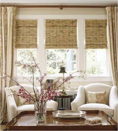 a living room filled with furniture next to a window covered in roman shades and drapes