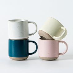 three coffee mugs stacked on top of each other in different colors and shapes,