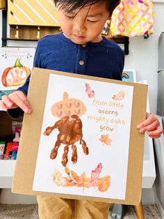 a young boy holding up a paper sign that says from little acorns mighty looks slow