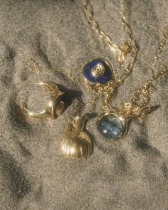 three necklaces are laying in the sand on top of each other and one is blue